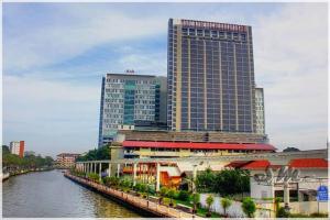 a tall building next to a river with buildings at D' Pines -Family Suite in Melaka