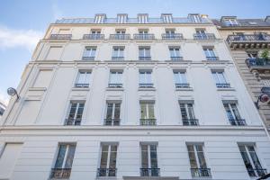 Edificio alto de color blanco con ventanas y balcones en Résidence Le Belleville, en París