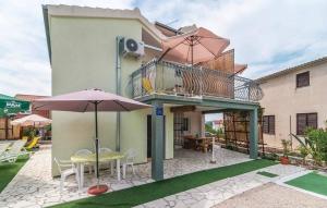 uma casa com um pátio com uma mesa e guarda-chuva em Holiday apartment in Razanj with terrace, air conditioning, WiFi, washing machine 4773-1 em Razanj