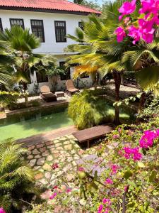 un complexe avec une piscine, des palmiers et des fleurs dans l'établissement Olma Colonial Suites, à Accra