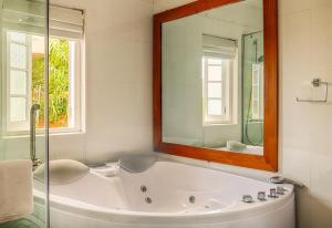 een badkamer met een bad en een grote spiegel bij The Clovelly Bungalow in Nuwara Eliya