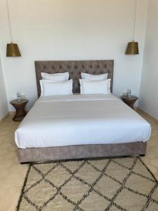 a bedroom with a large white bed with two pillows at Villa La Falaise in Oualidia