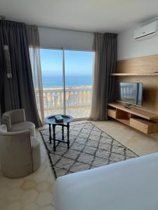 a living room with a bed and a tv and a couch at Villa La Falaise in Oualidia +37 photos