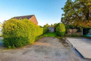 a hedge in front of a house with a driveway at Modern 4 Bed Chester Townhouse with FREE Parking in Christleton