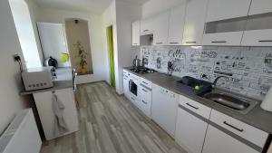 uma cozinha com armários brancos e um lavatório em Moderní klidný apartmán v přírodě, s parkováním. em Nové Město nad Metují