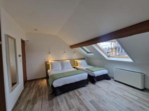 1 dormitorio en el ático con 2 camas y ventana en Hôtel De La Herse d'Or, en París