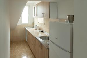 a kitchen with a white refrigerator and a sink at Apartman MENHETN Arandjelovac in Arandjelovac