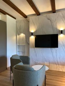 a living room with two chairs and a tv on a wall at Locanda Arizona in Bardolino