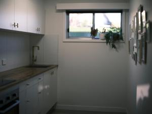 a kitchen with white cabinets and a window in it at Little Bell in Bellerive