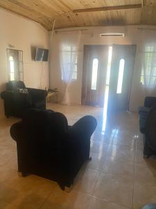 a living room with black couches and windows at 3-Bed House in Montego Bay 10 min from airport in Montego Bay