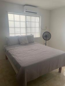 a bed in a room with a window and a fan at 3-Bed House in Montego Bay 10 min from airport in Montego Bay