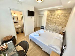 1 dormitorio con cama blanca y pared de piedra en Sperlonga Sul Mare, en Sperlonga