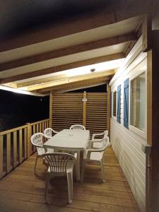 a white table and chairs on a wooden deck at Camping Domaine des Iscles in La Roque-dʼAnthéron