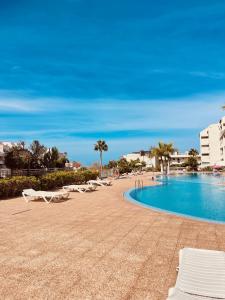 a swimming pool with white lounge chairs next to a beach at Palm Mar Penthouse Duplex in Palm-mar