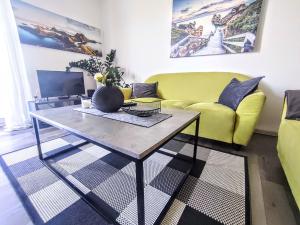 a living room with a yellow couch and a coffee table at Comfort Apartment for 6 & Loggia & Free Parking in Žilina