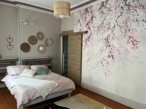 1 dormitorio con 1 cama y una pared con flores en Les Avatars en Saint-Amand-Montrond