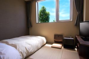 um quarto com uma cama, uma janela e uma cadeira em Hotel Futabatei em Hirono