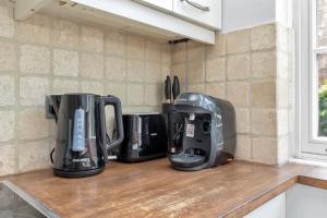 four coffeemakers sitting on a counter in a kitchen at Entire flat in heart of Chelsea hosted by Zahra in London