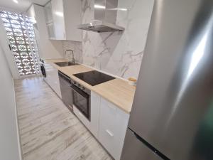 cocina con armarios blancos, fregadero y nevera en Apartamento 1134, en Zahara de los Atunes