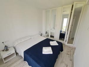 Dormitorio blanco con cama azul y espejo en Apartamento 1134, en Zahara de los Atunes