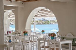 a restaurant with white tables and chairs and a view of the ocean at Nammos Hotel Mykonos in Psarou