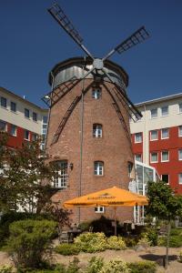 un paraguas naranja sentado frente a un molino de viento en Mühlenhotel Halle-Leipzig, en Landsberg