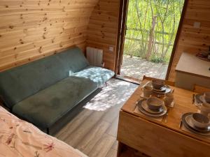 a room with a green couch and a table with dishes at Wind In The Willows Luxury Glamping in Peterborough