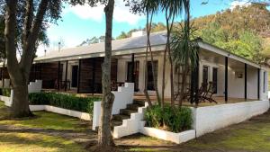 a white house with a porch and trees at Silvermist Wine Estate in Cape Town