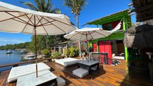 a deck with two umbrellas and chairs and a house at Casa Downtown in Caraíva