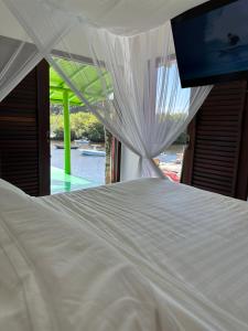 a white bed in a room with a window at Casa Downtown in Caraíva