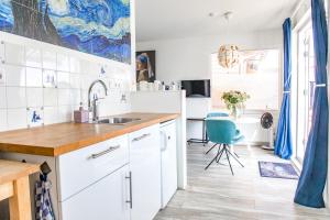 una cocina con armarios blancos y una silla azul en The New Lake Boathouse en Ámsterdam