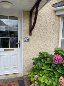 una puerta blanca al lado de una casa con flores en Faithlegg Estate, Mews Holiday Home, Waterford, en Waterford