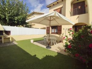 un patio con sombrilla frente a una casa en House with pool / Garden / BBQ BEACH, en Tarragona