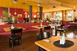 un restaurant avec des tables, des chaises et un canapé rouge dans l'établissement Mühlenhotel Halle-Leipzig, à Landsberg