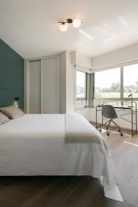 a bedroom with a large white bed and a desk at Someso Apartamentos Turisticos in A Coruña