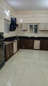 a large kitchen with wooden cabinets and a large floor at SHI's Vilva AC 2BHK in Coimbatore