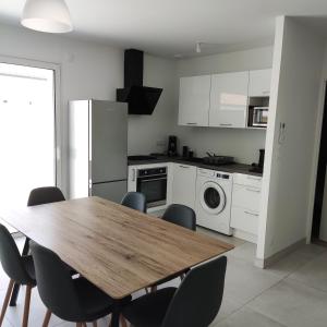 a kitchen with a table and chairs and a refrigerator at Maison neuve à 13 min des Sables in Talmont