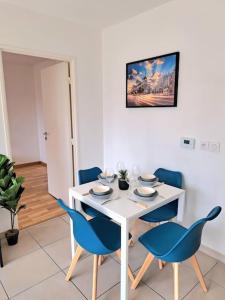 a white table with blue chairs in a room at Casa Rosa : appartement moderne avec balcon in Tassin-la-Demi-Lune