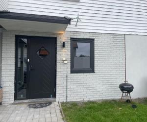 a black door on a white brick house with a grill at Larvik appartment in the city in Larvik