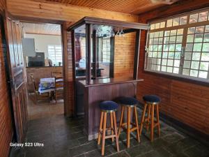 un bar en una cabina con taburetes en una habitación en Chácara Belvedere.Espaço rural, descanso e lazer en Londrina