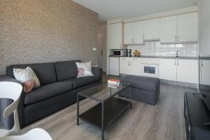 a living room with a couch and a table and a kitchen at Someso Apartamentos Turisticos in A Coruña