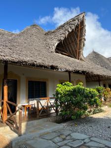a house with a thatched roof with a table outside at BeB Sardegna2 Anjumasa village in Watamu