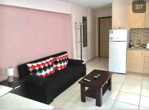 a living room with a black couch and a refrigerator at Ismini Cozy Rooms in Kavala