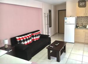 a living room with a black couch and a refrigerator at Ismini Cozy Rooms in Kavála