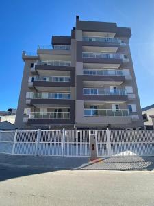 Un edificio alto con una valla blanca delante. en Apartamento Ubatuba 405, en Ubatuba