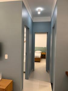 Un pasillo que conduce a un dormitorio con paredes azules. en Apartamento Ubatuba 405, en Ubatuba 12 fotos más