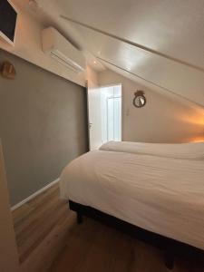 1 dormitorio con cama blanca y ventana en Boetje 51, en Den Burg