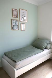 a white bed with four pictures on the wall at Ferienwohnung Sieben Eulen in Garrey (Hoher Fläming) 