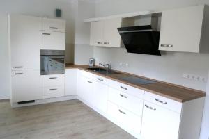 a white kitchen with white cabinets and a sink at Ferienwohnung Sieben Eulen in Garrey (Hoher Fläming) 