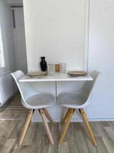 une table à manger blanche avec deux chaises blanches et une table dans l'établissement Upea yksiö Kotkan Katariinassa, à Kotka